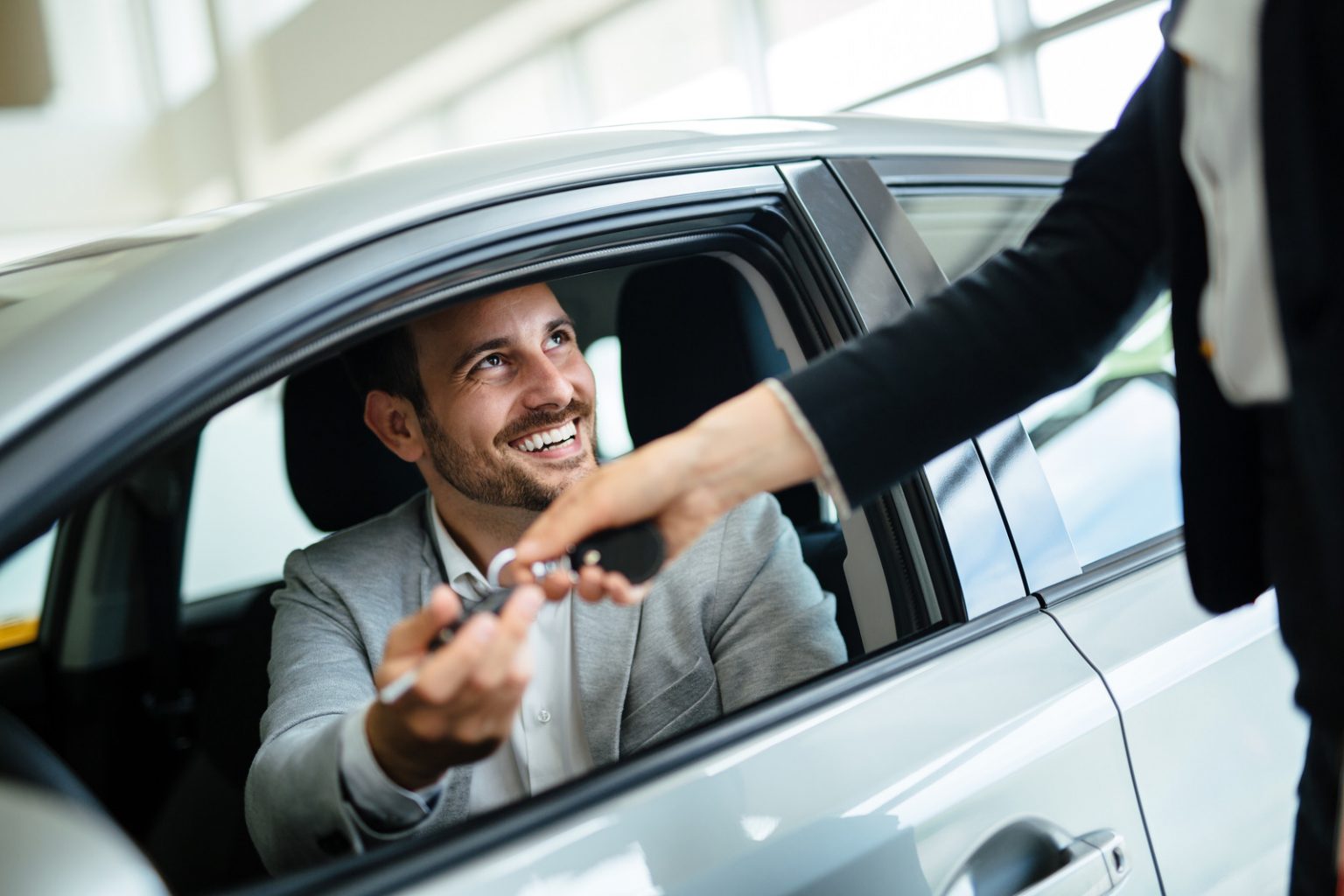 alt="Professional woman salesperson during work with customer at car dealership."