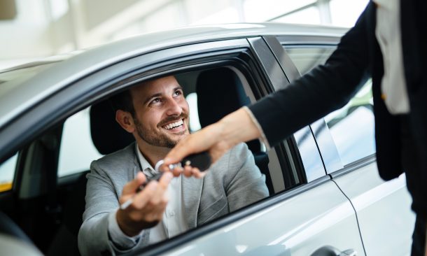alt="Professional woman salesperson during work with customer at car dealership."