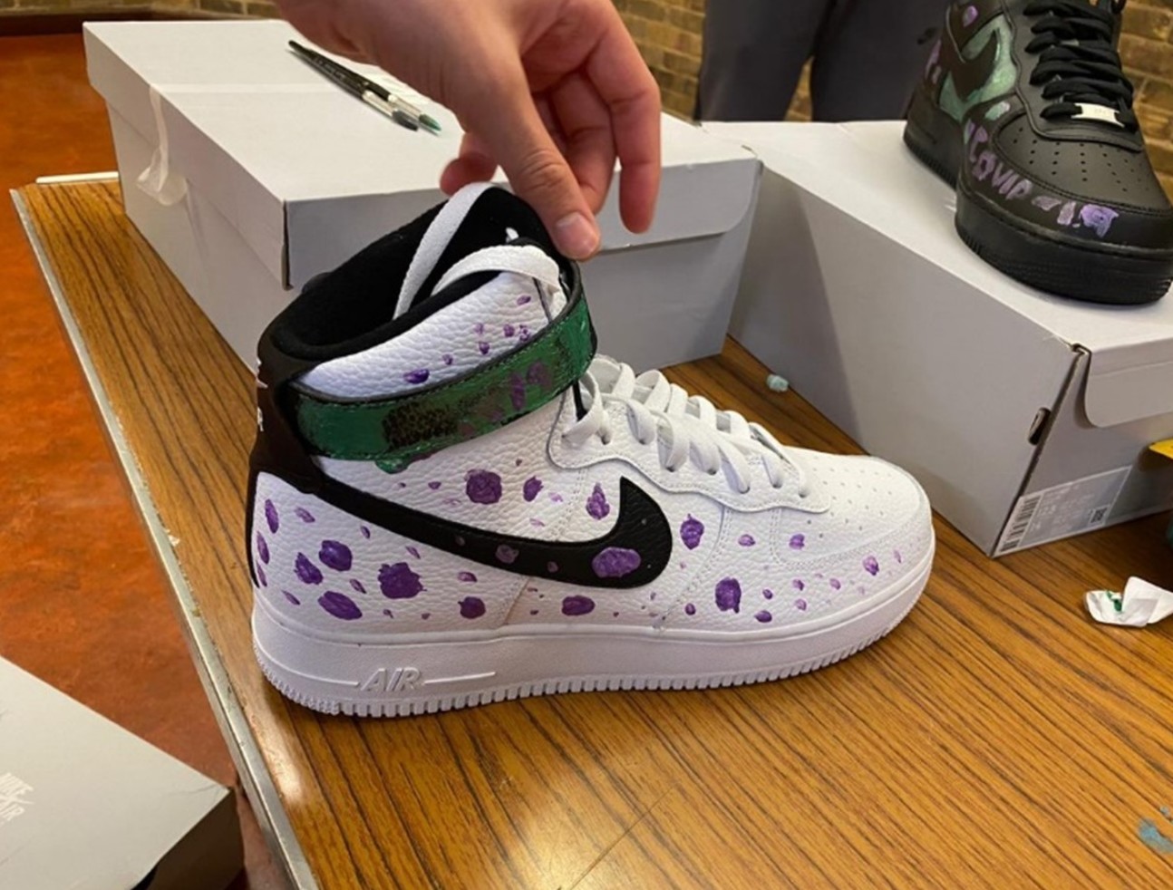 A white nike sneaker with purple dots painted on