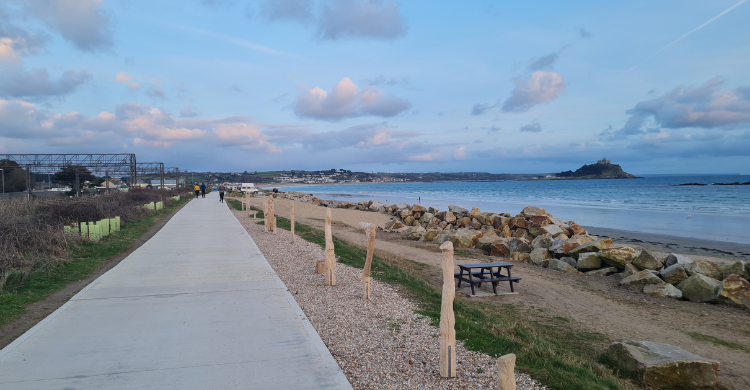 Concrete path running alongside a beach with St Michael's Mount in the distance