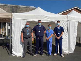 four health professionals standing in front of a vaccination tent