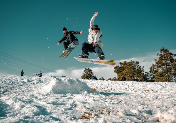 man in black and white jacket riding on snowboard during daytime