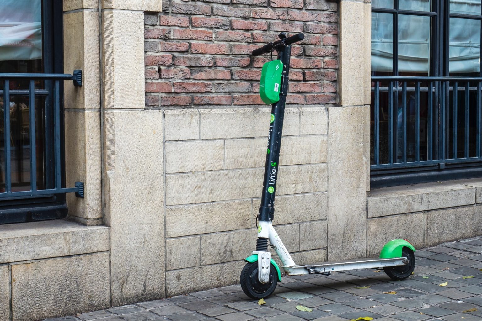 E-Scooters in the UK: Are They Legal and What Does the Future Hold? white and green scooter parked beside wall