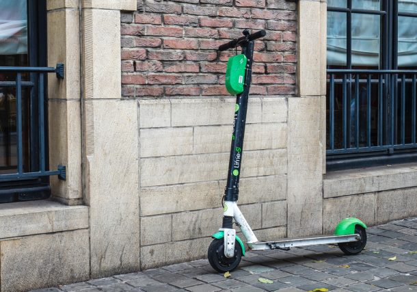white and green scooter parked beside wall
