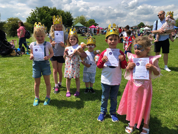 Six children dressed in fancy dress holding up winners certificates