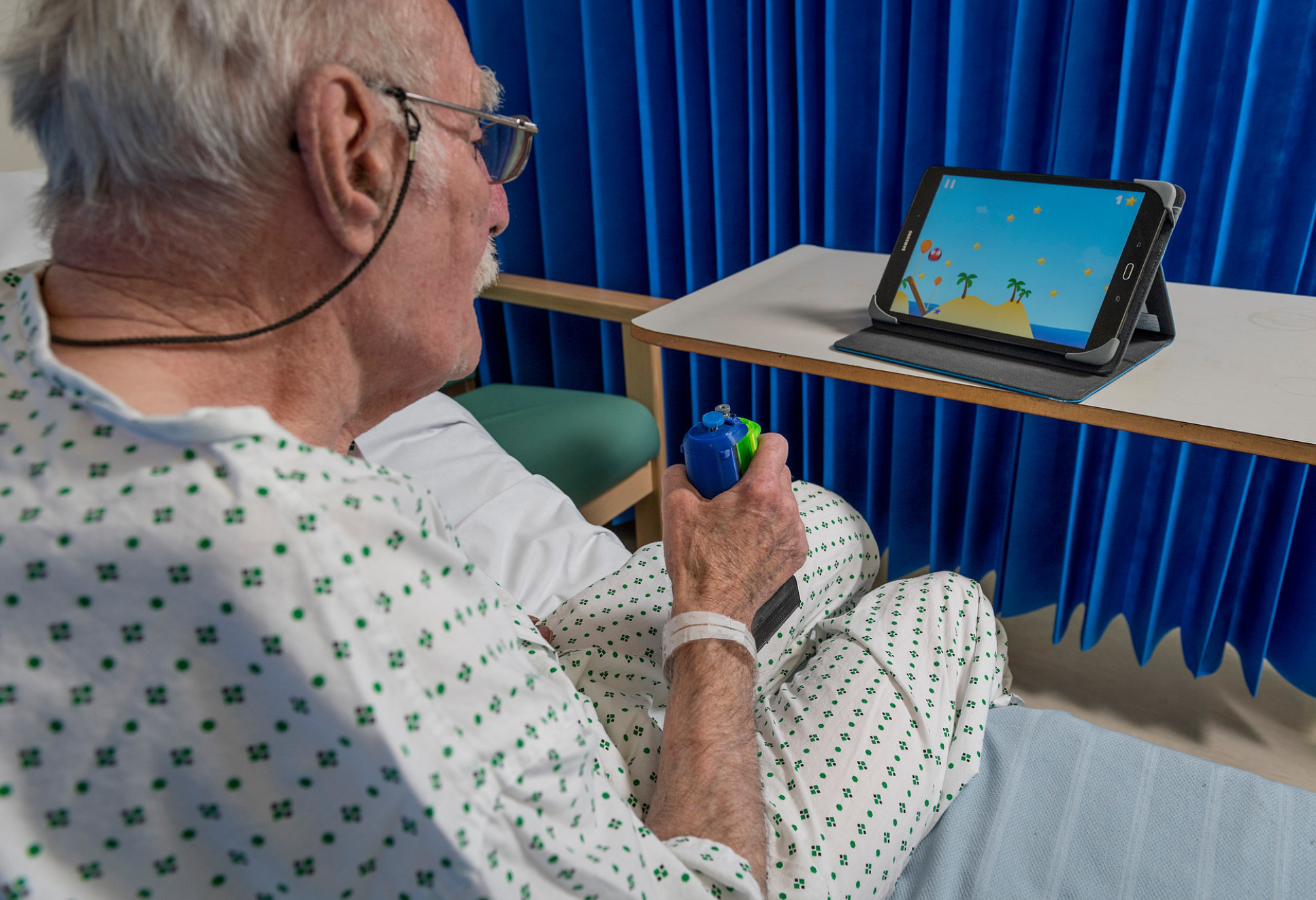An elderly man uses the gripable device to play a game on an iPad
