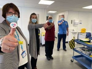 Four Blackpool Victoria Hospital vaccine staff hold up vaccine stickers