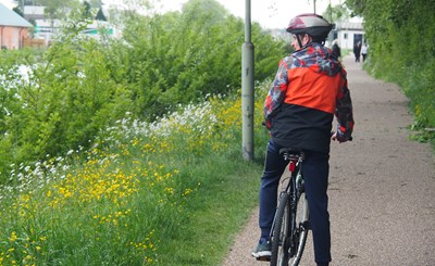 Cyclist on a path wearing an orange coat
