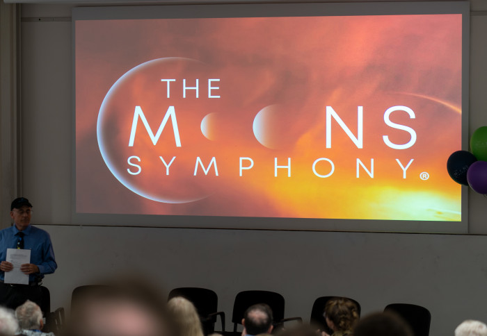A screen projecting the words The Moons Symphony