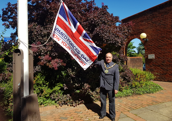 Chairman of the Council holding the Armed Forces Flag ahead of it being raised at the council offices