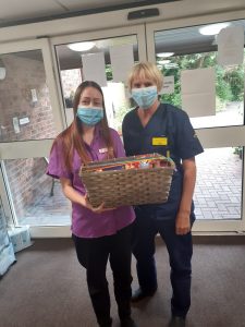 Infection control nurse and care home project lead stood holding hamper