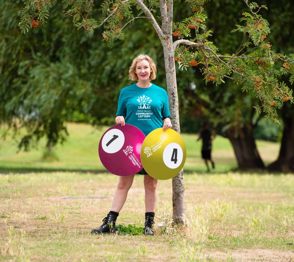 Councillor Claire Malcolmson holding large lottery balls in Meadowbank Park in Dorking.