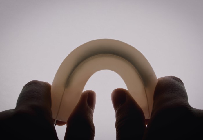 Photo of two hands holding up the SqueezAble device