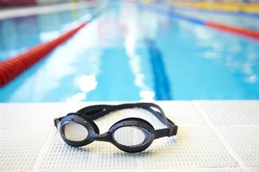 Pair of swimming goggles by the side of a swimming pool