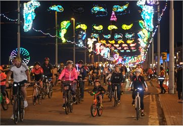 Cyclists riding down brightly illuminated road at night