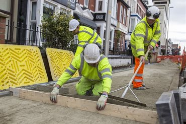 Three workmen laying footpath.
