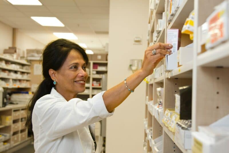 A pharmacist reaching for something off a shelf