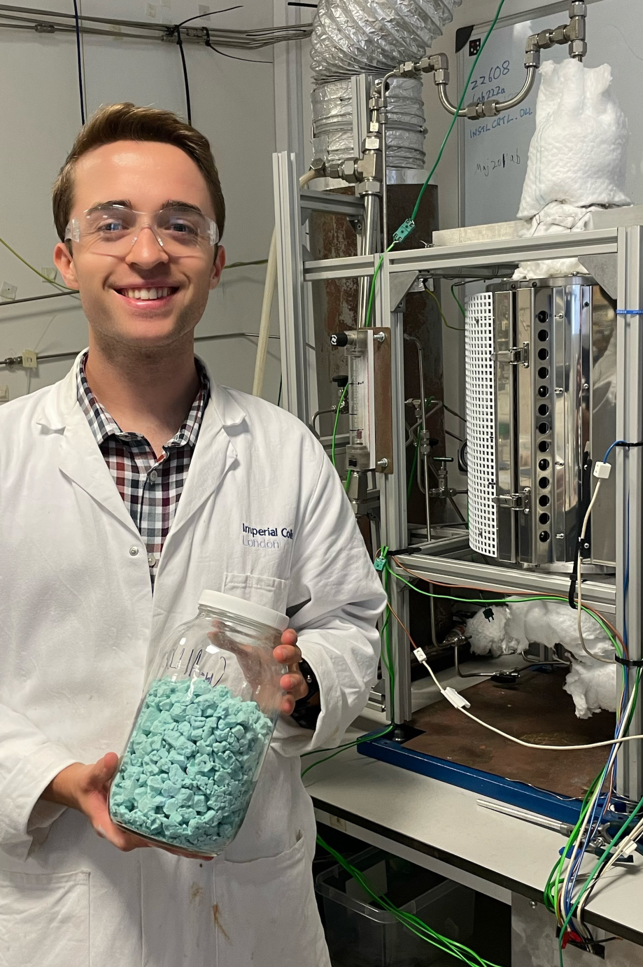 Lead author and PhD candidate Michael High smiles as he holds up a jar of the materials needed for redox reactions