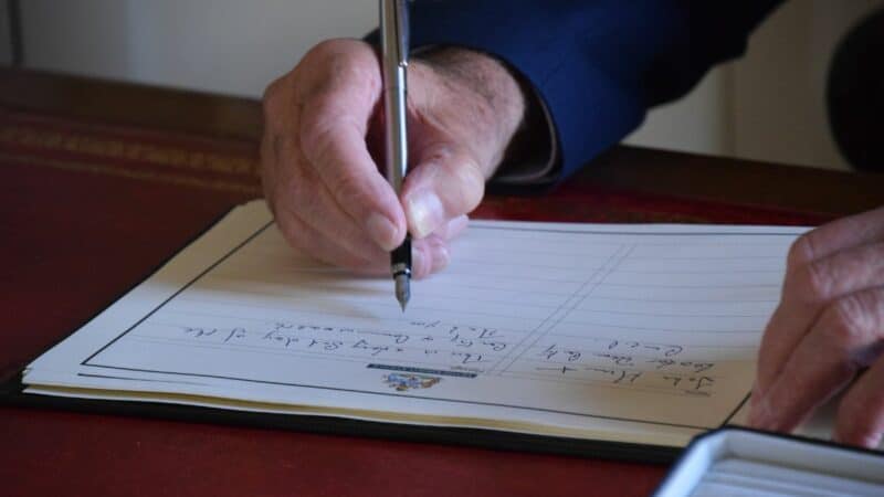 A hand signing the Book of Condolence