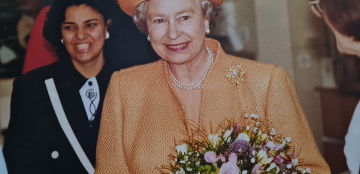 Her Majesty Queen Elizabeth II on her visit to Scunthorpe General Hospital in May 1993. She is wearing a peach jacket and hat and carrying a large bouquet of flowers