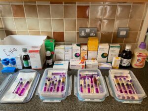 Kitchen worksurface covered in bottles of medication and syringes
