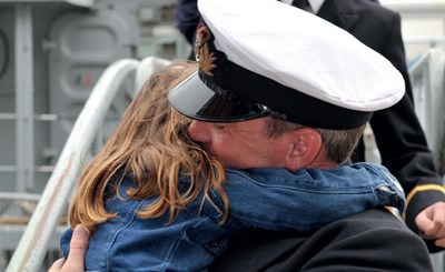 little girl hugging father wearing armed forces uniform
