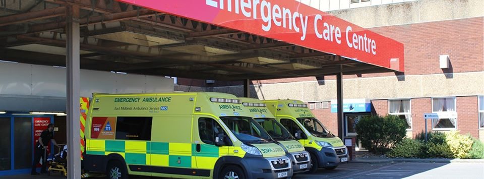 2 ambulances parked up under an emergency care centre sign