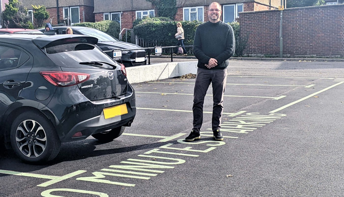 Councillor Clayton Welmman stading next to a car and 30 minute free parking bay in Southside car park ne