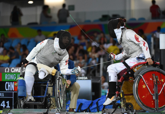 Image of two athletes taking part in a professional wheelchair fencing match.