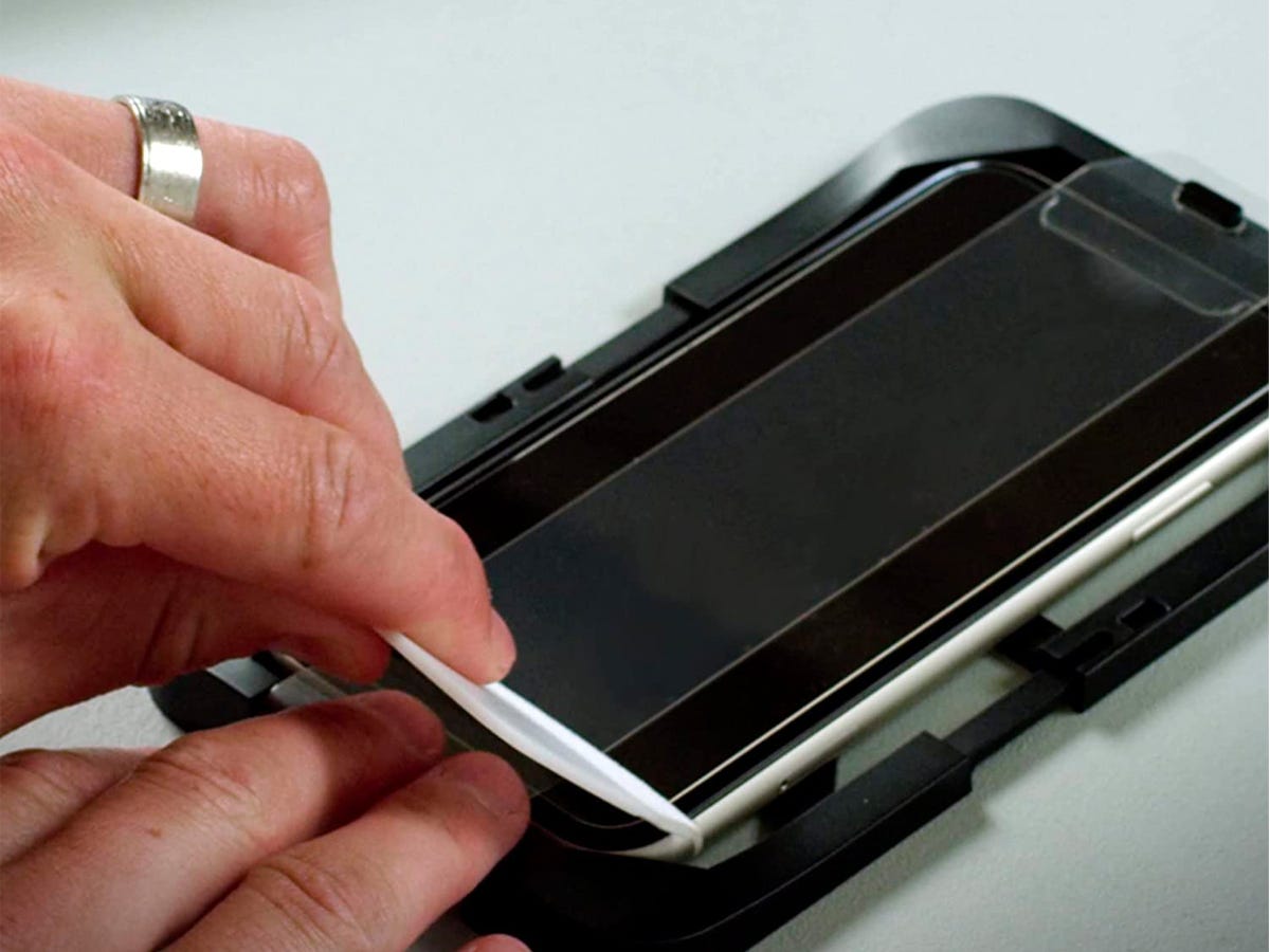 Person installing the Otterbox Amplify Glass Screen Protector on an iPhone.