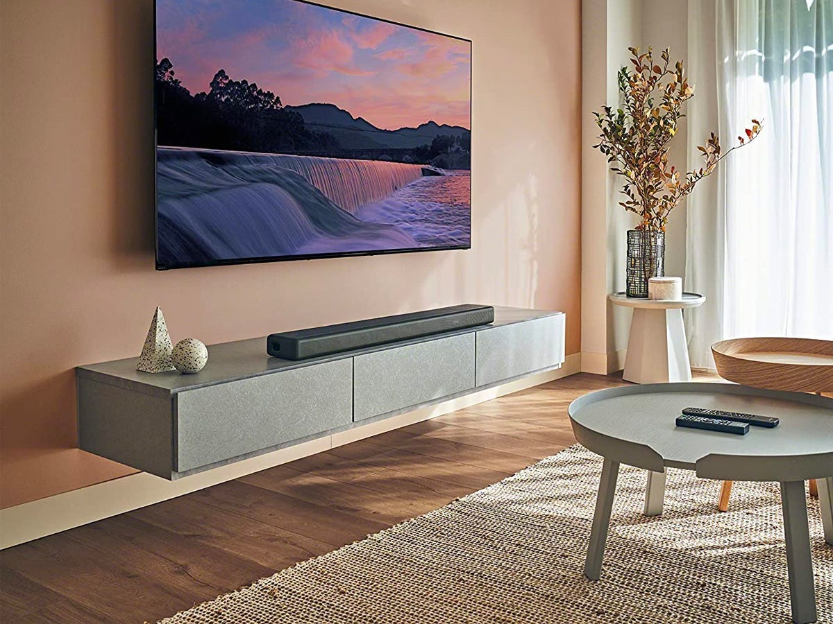 A Sony HT-A3000 3.1ch Dolby Atmos Soundbar sits on a floating TV stand below a wall-mounted flatscreen TV.