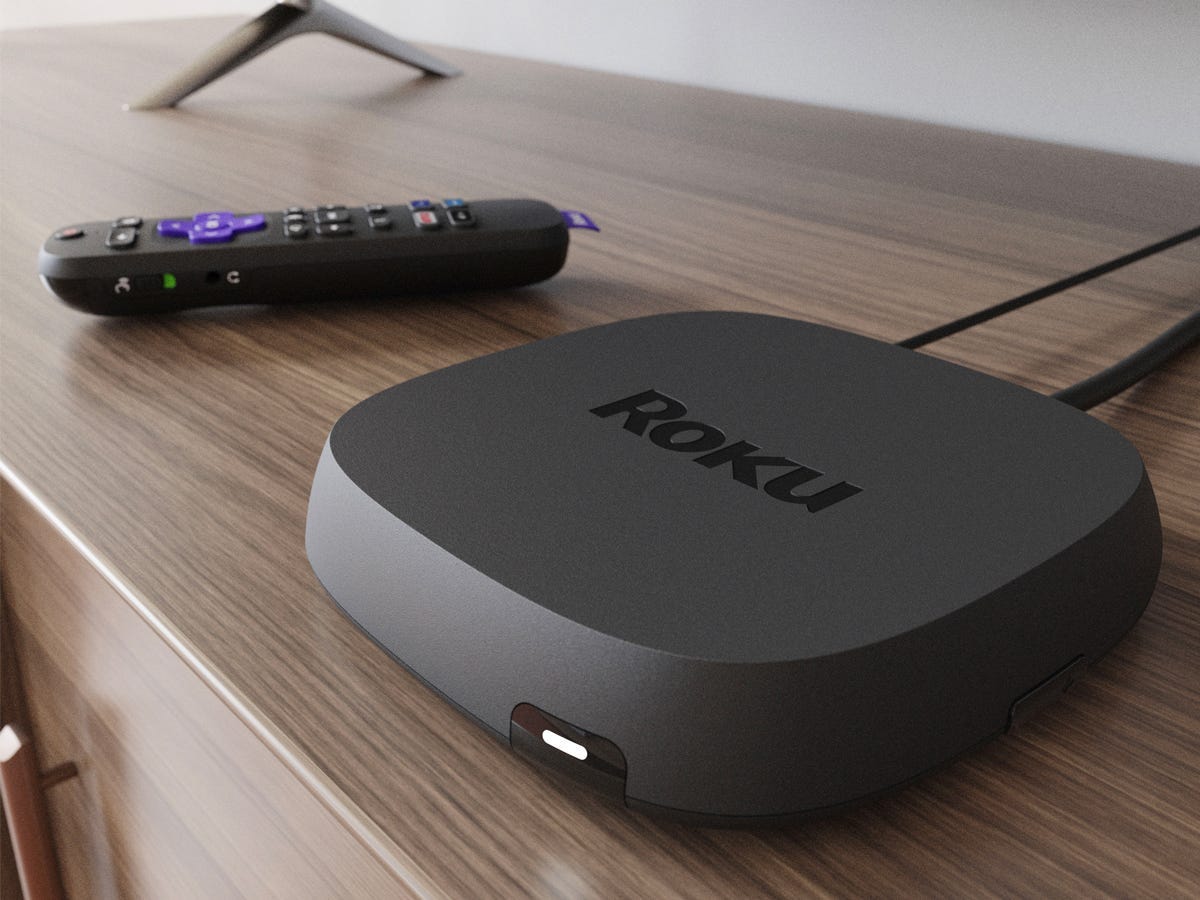 Roku Ultra streaming device and remote on a media stand below a tv.