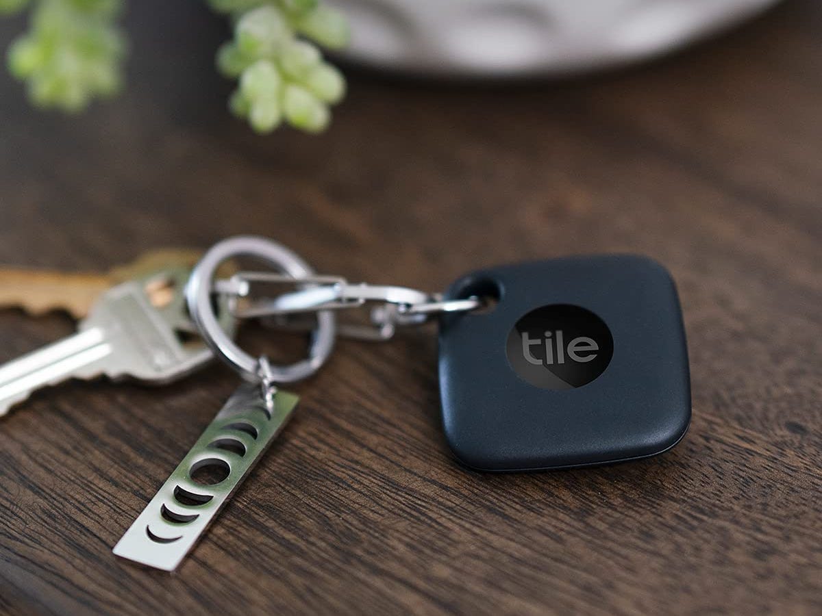 Tile Mate tracker attached to a key ring, set on a wooden surface.