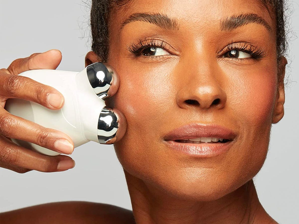 A person uses the NuFace Trinity Starter Kit to tone the skin on their face.