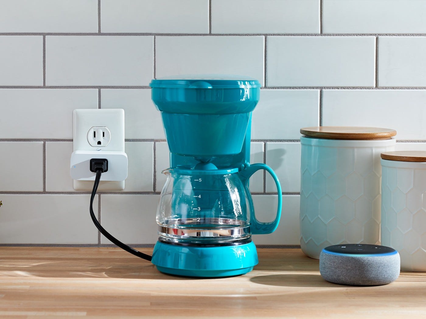 Coffee maker on a kitchen counter plugged into an outlet with Amazon smart plug.