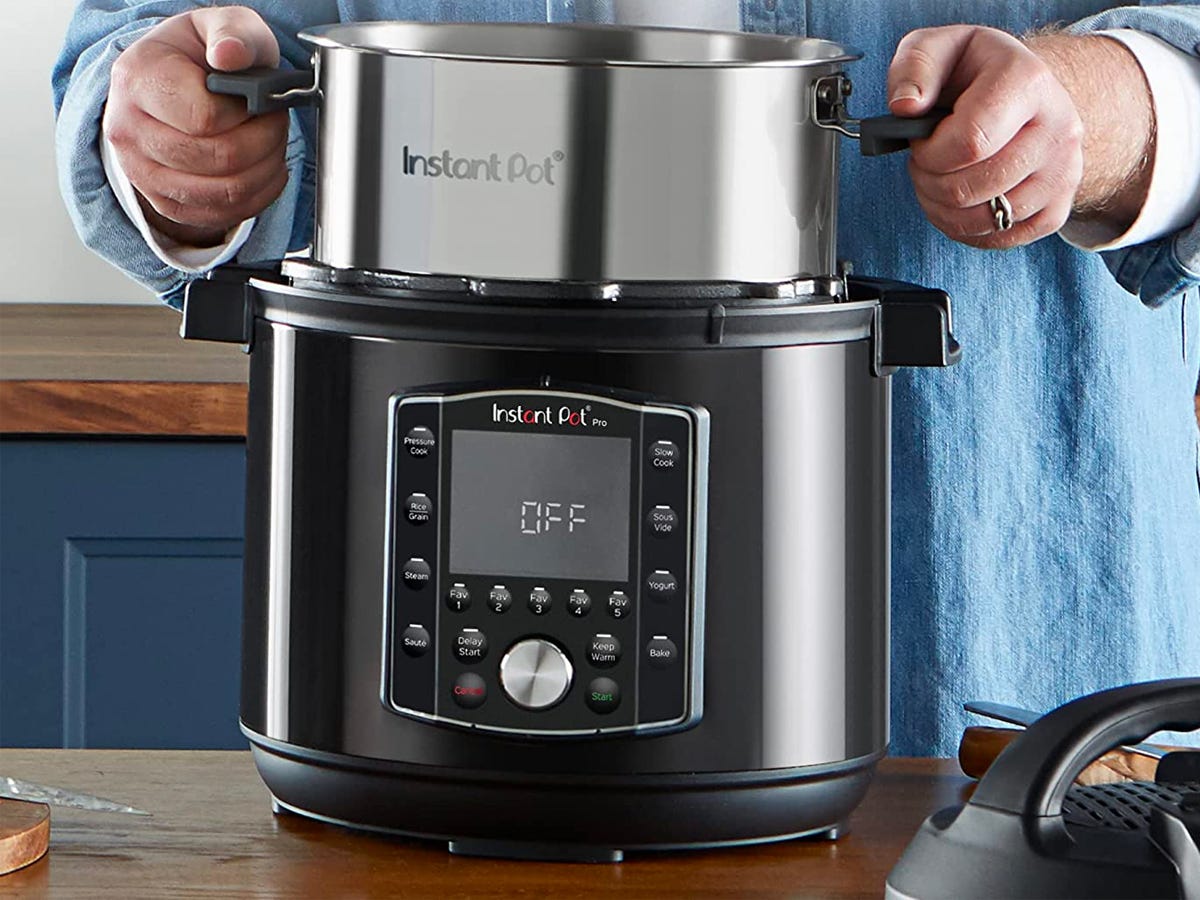 A person removes the inner pot from a 6-quart Instant Pot Pro 10-in-1 Pressure Cooker.