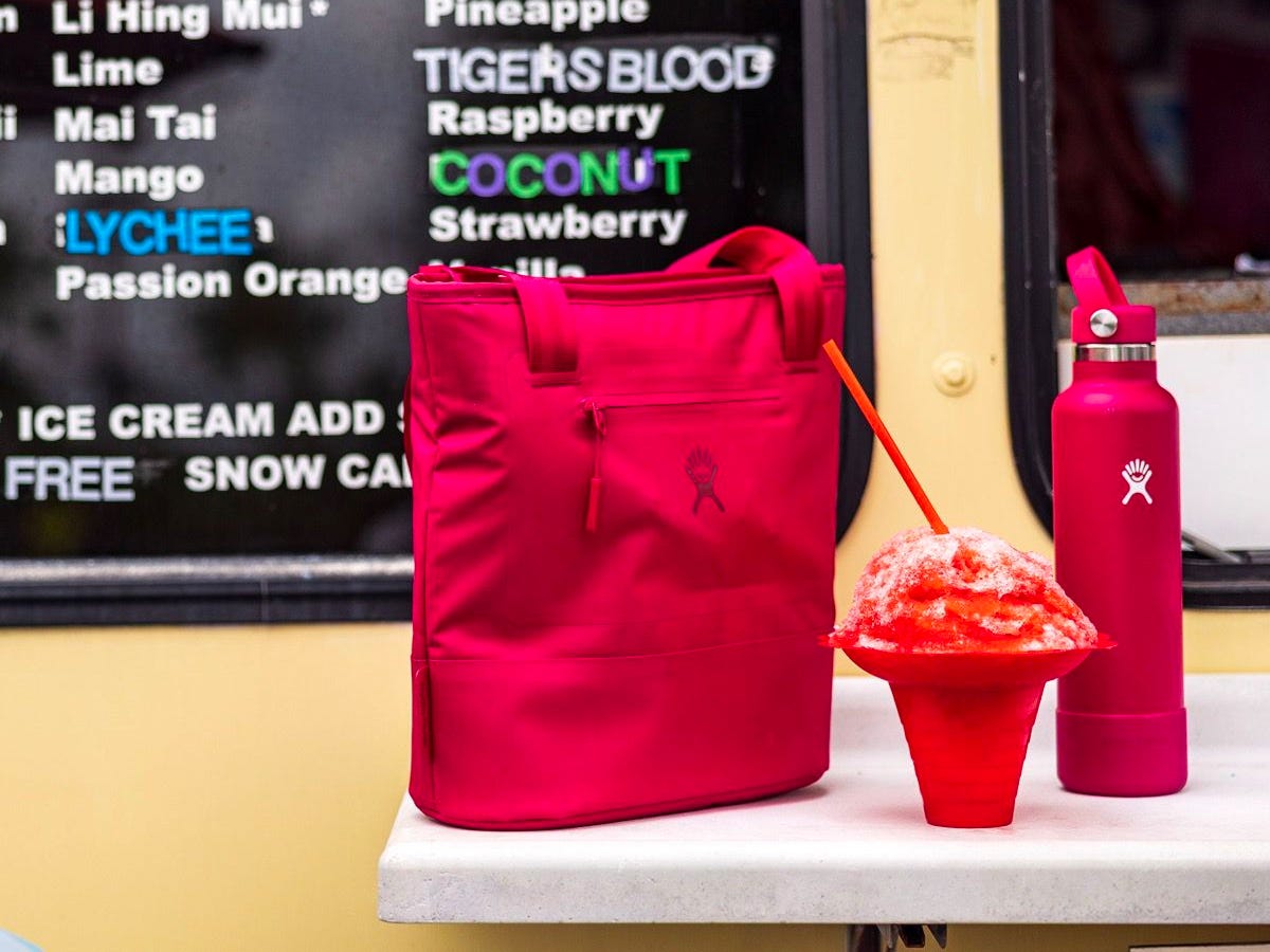 A Hydro Flask Lunch Tote (8L) sits on a table next to a snow cone an a Hydro Flask bottle.