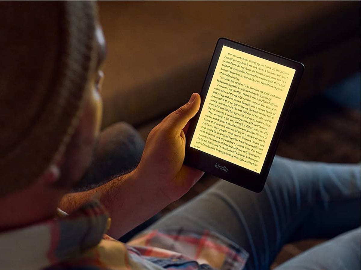 A person reading on the Kindle Paperwhite with it's LED backlight lit up, one of the best gift ideas on sale for Cyber Monday