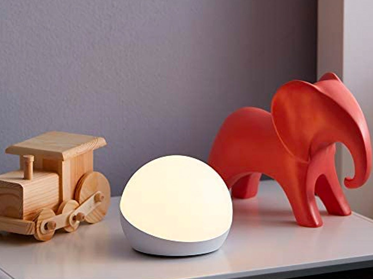 Amazon Echo Glow smart lamp on a table next to two wooden toys.