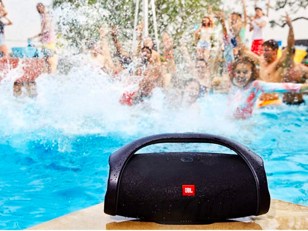 The JBL Boombox 2 sitting by a pool with a bunch of people playing in it.