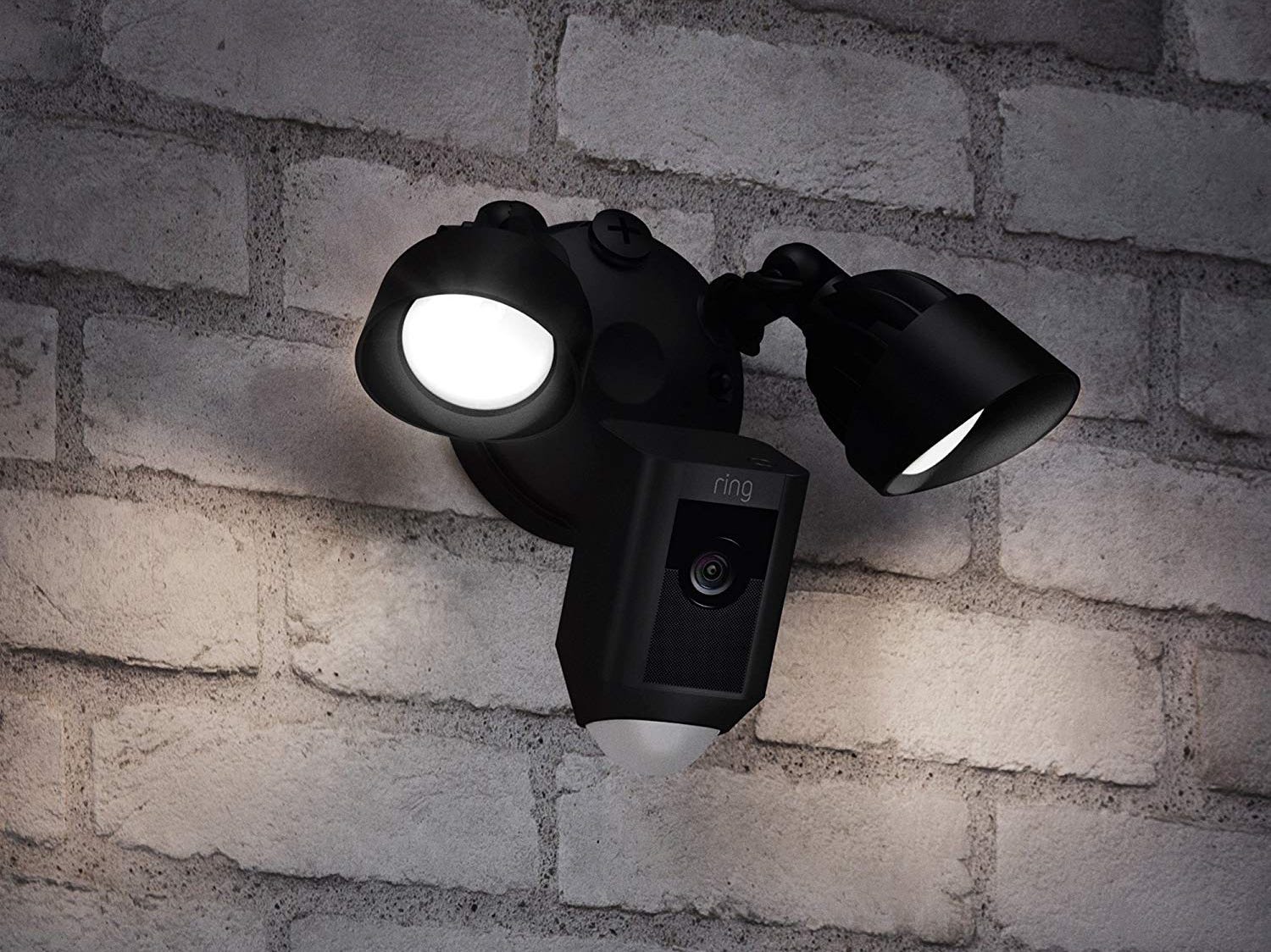 ring floodlight camera attached to a brick exterior wall of a house.