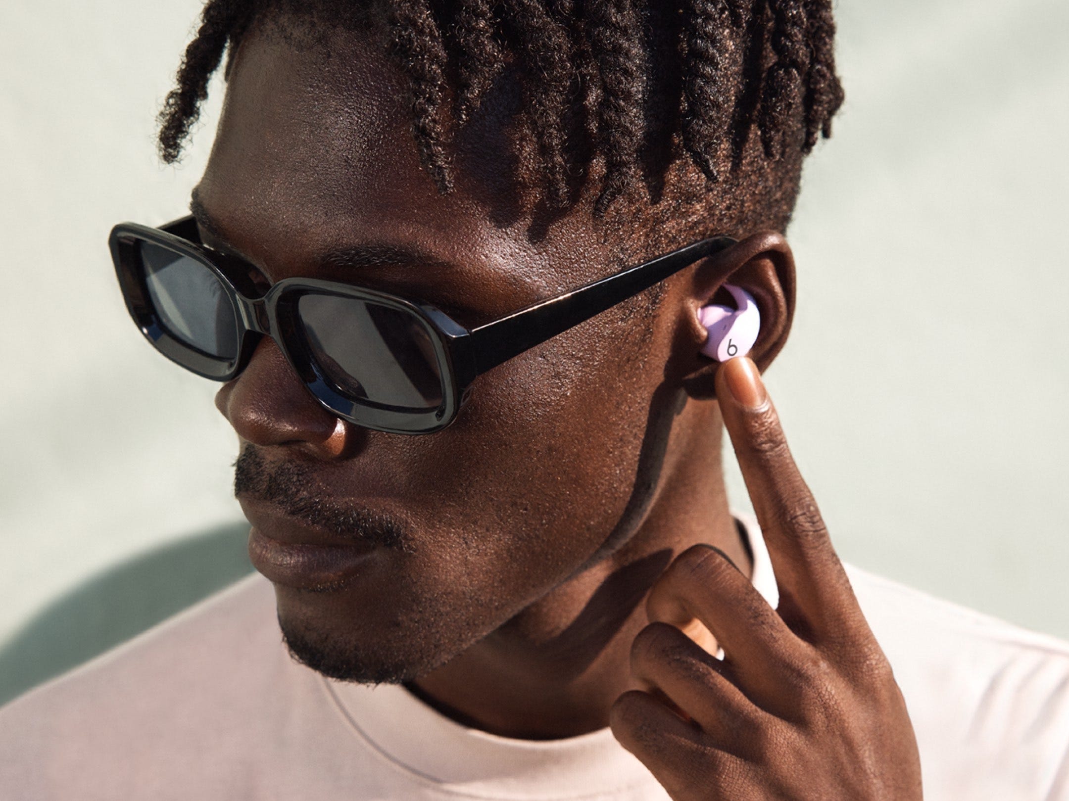 a person wearing sunglasses and the beats fit pro in lavender