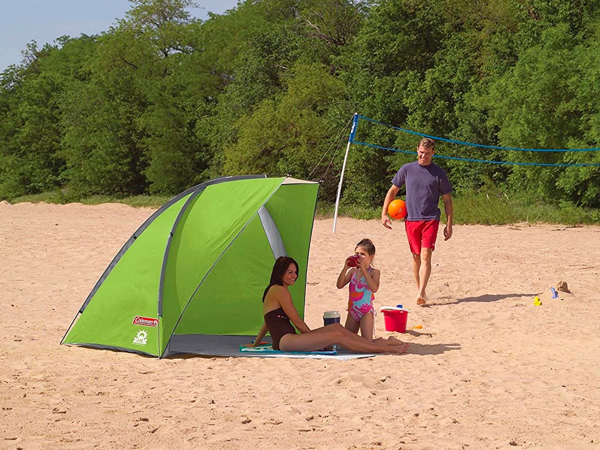 A family relaxes under the shade of a Coleman Beach Sun Shelter while at the beach.