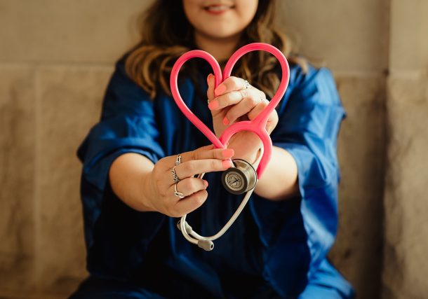 girl in blue jacket holding red and silver ring