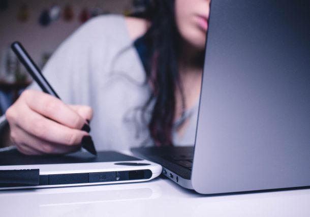 woman using drawing pad while sitting in front of laptop
