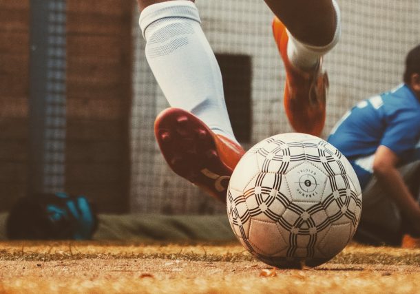 person in white and red soccer jersey kicking soccer ball