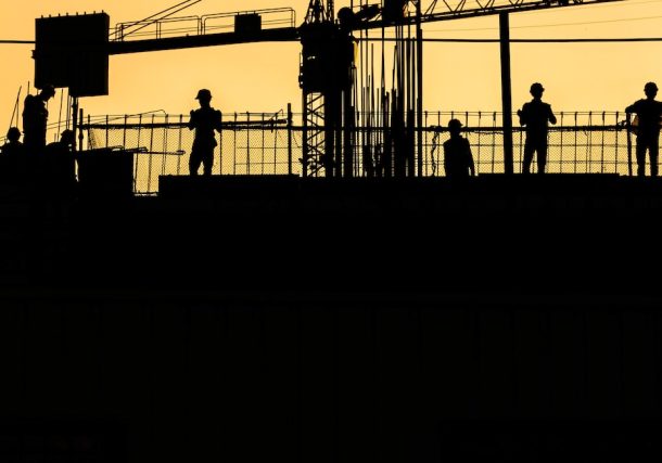 silhouette of people standing on tower crane during night time