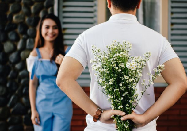 Man Holding Baby's-breath Flower in Front of Woman Standing Near Marble Wall