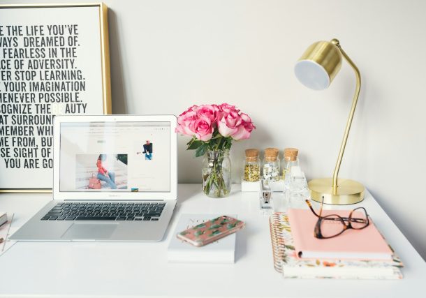 MacBook Air beside gold-colored study lamp and spiral books