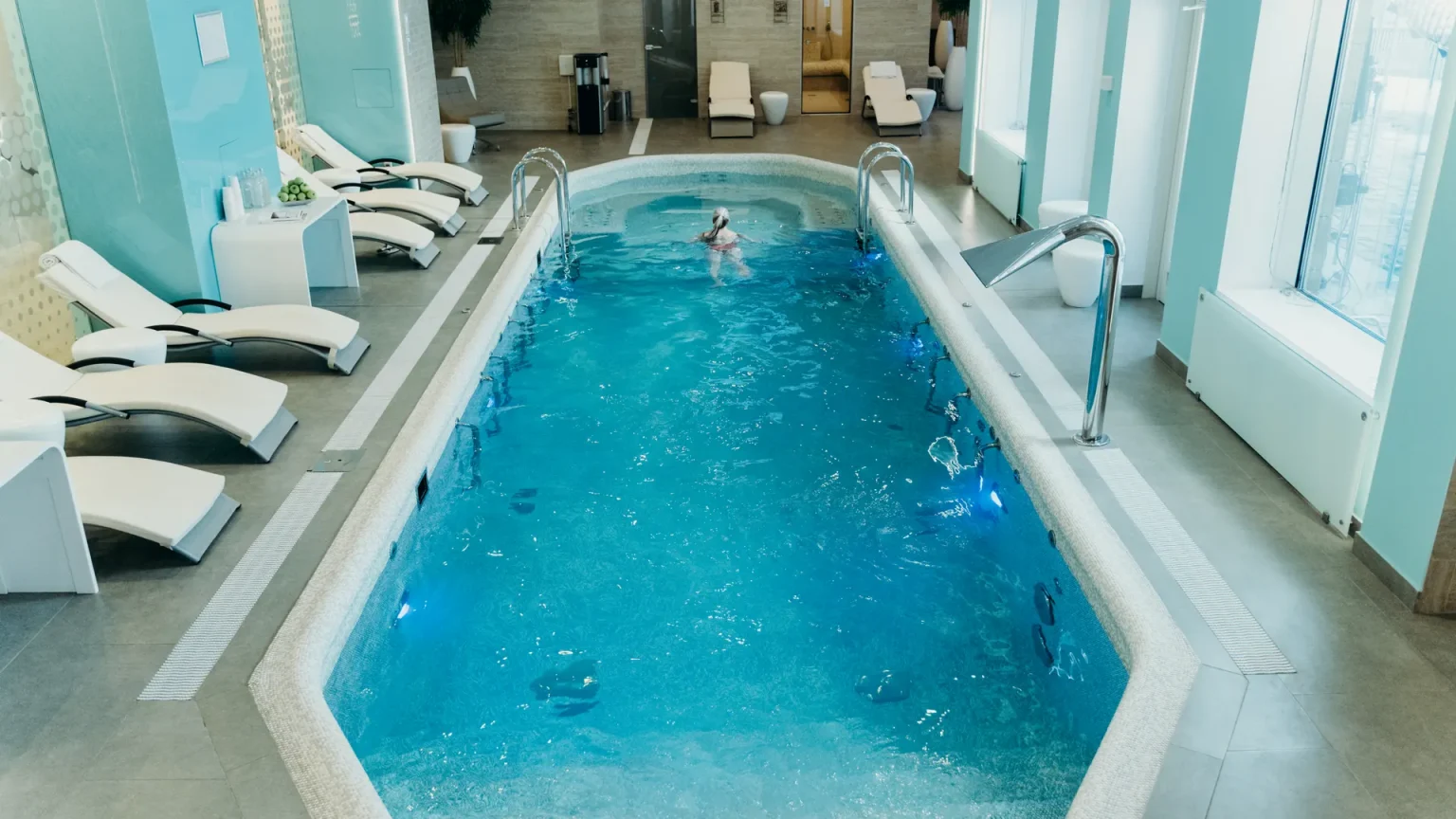 Indoor hotel spa pool with loungers and sauna access